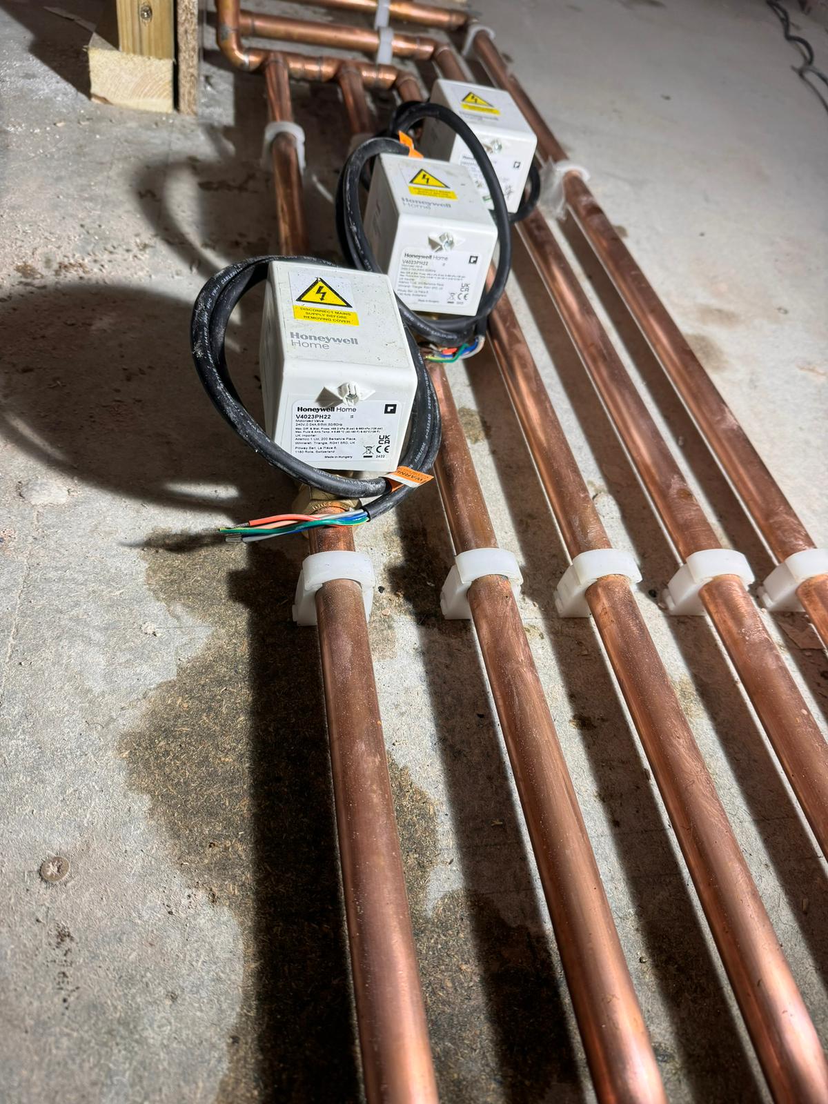 Neatly run copper heating pipes with Honeywell Home motorised zone valves ready for connection