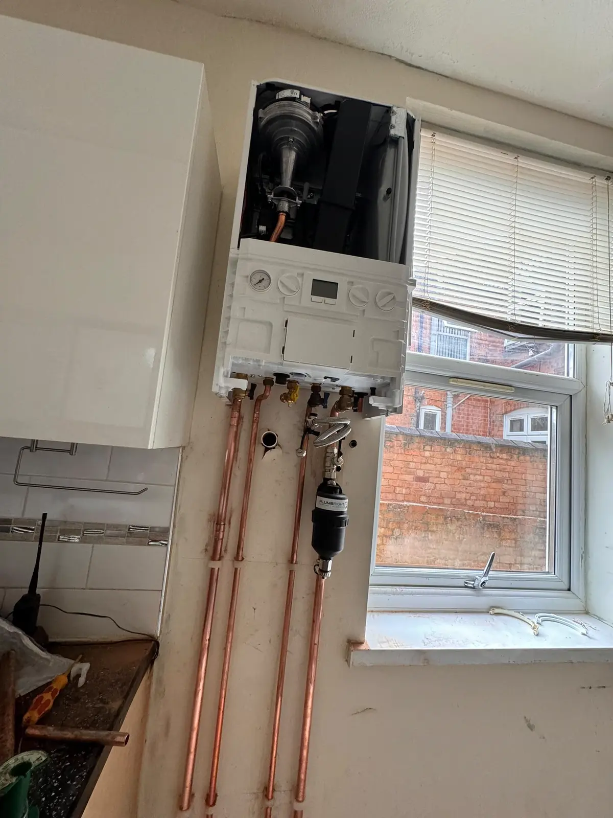 Combi boiler with the front casing removed, exposing the fan and heat exchanger while work is carried out