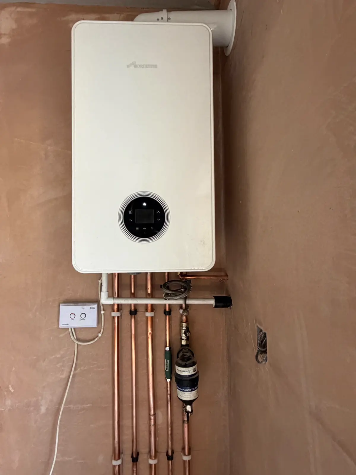 Worcester combi boiler and horizontal flue on a freshly plastered wall, with copper drops and a filter below