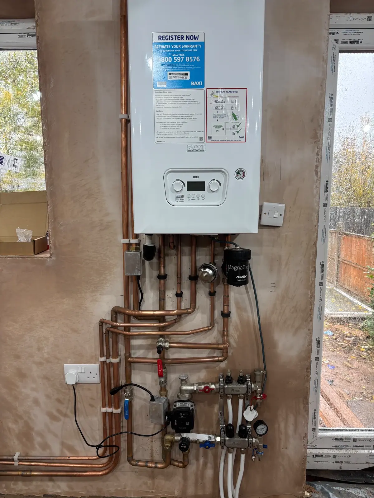Baxi combi boiler on new copper pipework above a heating manifold with a circulating pump, flow gauges and a magnetic filter