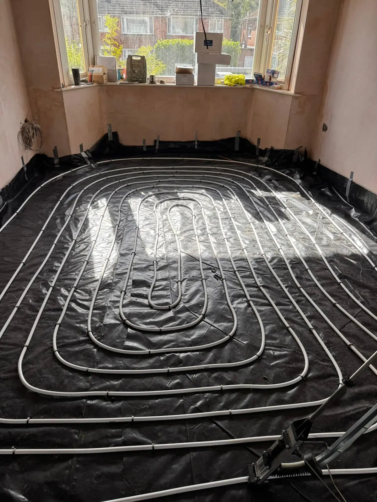 Wide view of underfloor heating loops over membrane across a room, ready for screed